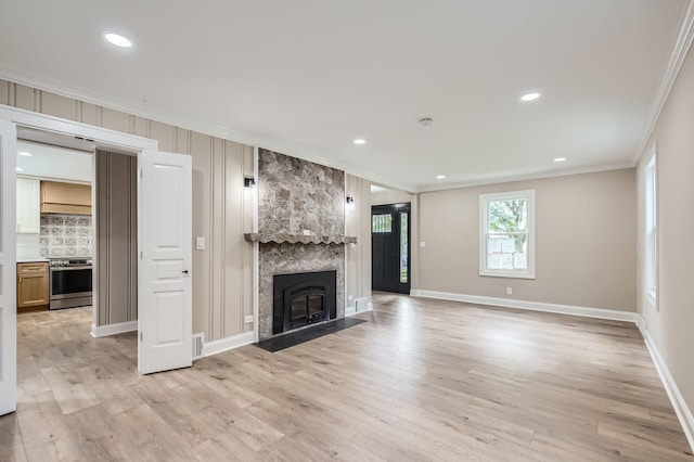 unfurnished living room with ornamental molding, light wood-style flooring, baseboards, a fireplace, and recessed lighting