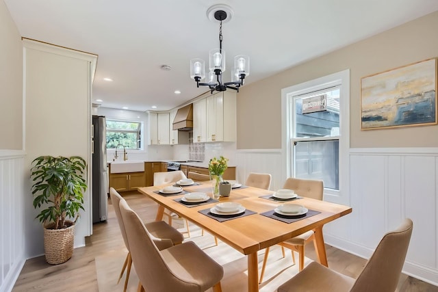 dining room featuring a wainscoted wall, a chandelier, light wood-style floors, a decorative wall, and recessed lighting