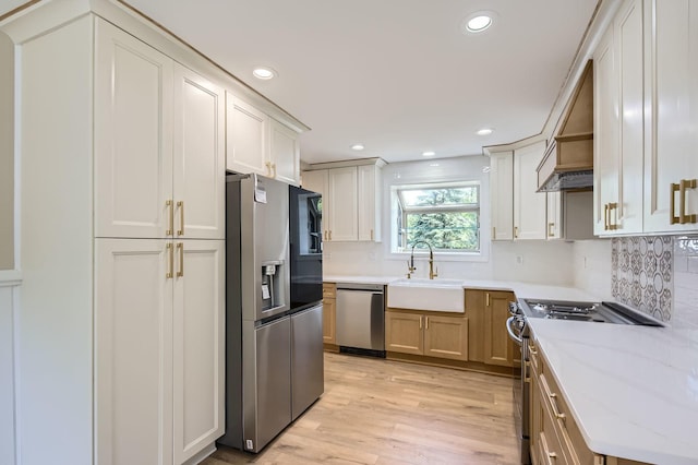 kitchen with appliances with stainless steel finishes, a sink, recessed lighting, backsplash, and light wood-style flooring