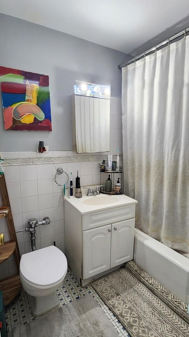 6030 N Sheridan Rd Unit 404, Chicago, IL 60660 - full bath featuring tile walls, vanity, shower / tub combo with curtain, and toilet