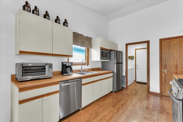 2805 Susan Stone Dr, Urbana, IL 61802 - kitchen with appliances with stainless steel finishes, a sink, light countertops, washer / dryer, and light wood-style flooring