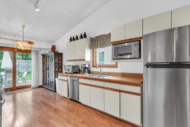 2805 Susan Stone Dr, Urbana, IL 61802 - kitchen with stainless steel appliances, a sink, lofted ceiling, a textured ceiling, and light wood-style floors