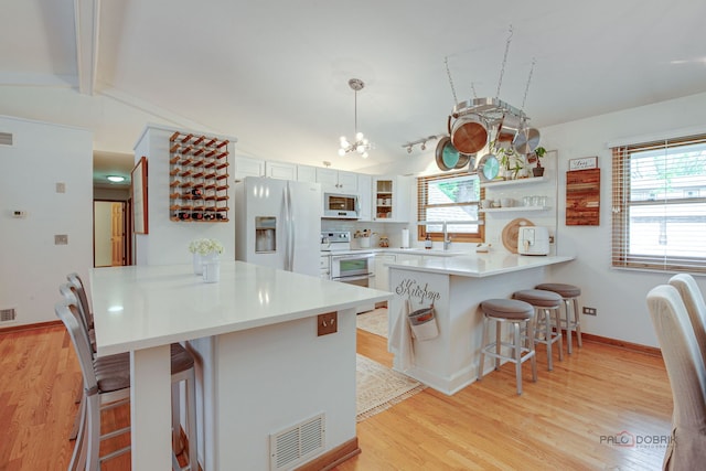 6316 Lake Shore Dr, Cary, IL 60013 - kitchen featuring white appliances, a peninsula, open shelves, a kitchen bar, and a chandelier