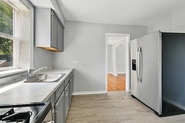 12137 S Perry Ave, Chicago, IL 60628 - kitchen featuring stainless steel appliances, gray cabinets, a sink, light wood-style floors, and light countertops