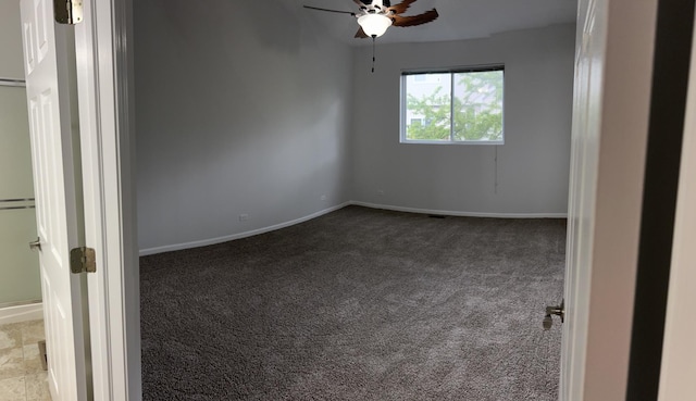 empty room with carpet floors, a ceiling fan, and baseboards
