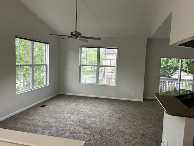 empty room with dark colored carpet, lofted ceiling, baseboards, and ceiling fan