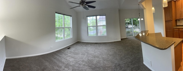 unfurnished living room featuring ceiling fan, dark carpet, baseboards, and lofted ceiling