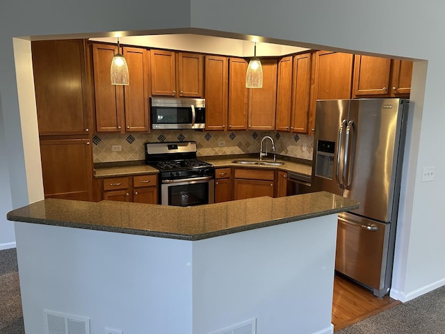 kitchen with appliances with stainless steel finishes, a sink, brown cabinets, backsplash, and baseboards
