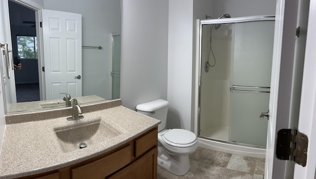 bathroom featuring a shower stall, toilet, and vanity