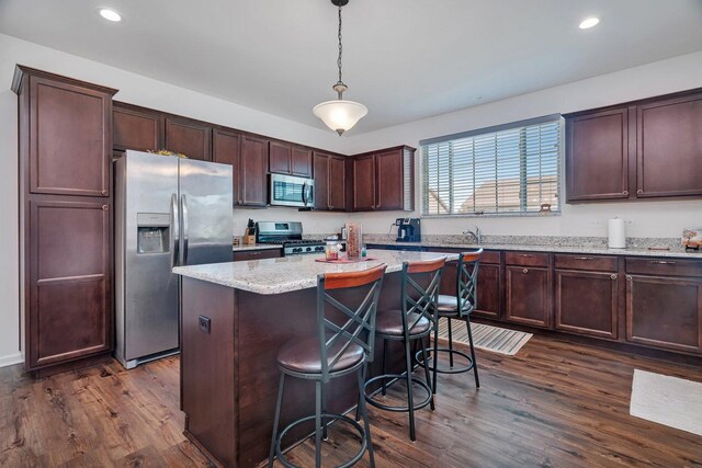 25626 S Geraldine Ct, Channahon, IL 60410 - kitchen featuring appliances with stainless steel finishes, dark wood-style flooring, a center island, a breakfast bar, and pendant lighting