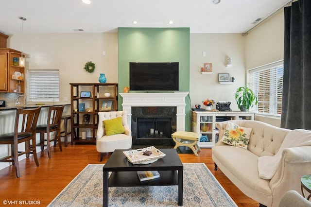 living area featuring wood finished floors, recessed lighting, and a premium fireplace