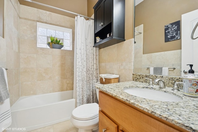 full bathroom with toilet, shower / tub combo with curtain, tile patterned floors, vanity, and tile walls
