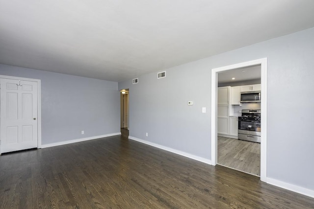 spare room featuring dark wood finished floors and baseboards