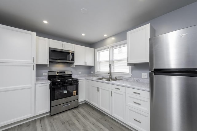 kitchen featuring appliances with stainless steel finishes, a sink, light countertops, white cabinetry, and recessed lighting