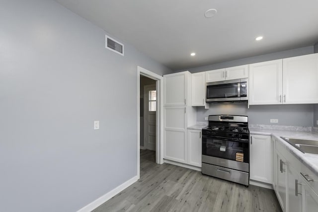 kitchen featuring appliances with stainless steel finishes, light wood-style flooring, white cabinetry, recessed lighting, and light countertops
