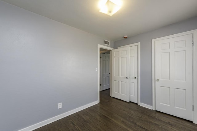 unfurnished bedroom featuring baseboards, dark wood-type flooring, and a closet