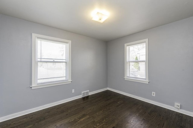 spare room featuring dark wood-type flooring and baseboards