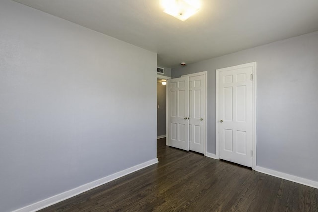 unfurnished bedroom with baseboards and dark wood-style flooring