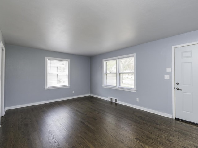 unfurnished living room with plenty of natural light, baseboards, and dark wood finished floors