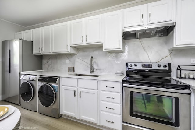 kitchen with stainless steel appliances, under cabinet range hood, a sink, washing machine and clothes dryer, and light countertops