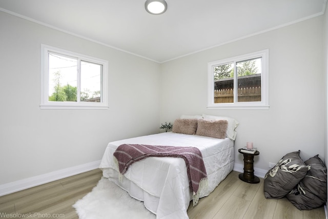 bedroom featuring wood finished floors, baseboards, and ornamental molding