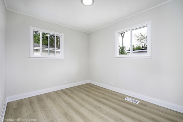 unfurnished room featuring healthy amount of natural light, wood finished floors, baseboards, and crown molding