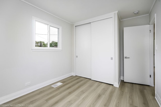 unfurnished bedroom featuring crown molding, wood finished floors, a closet, and baseboards
