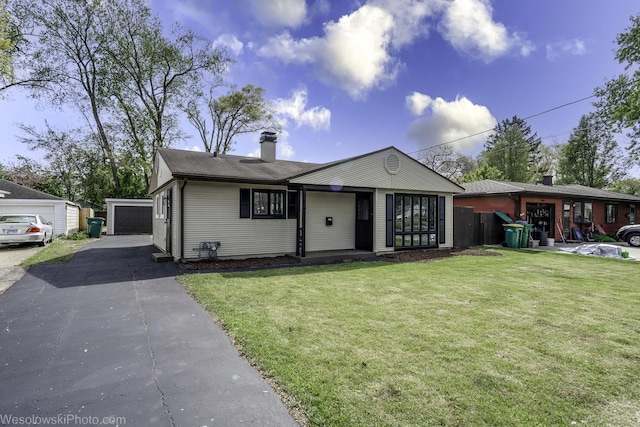 ranch-style home with a front yard, a chimney, an outdoor structure, and a detached garage