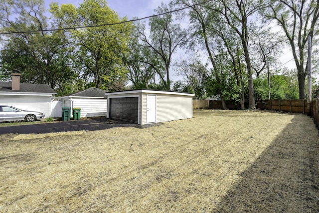 view of yard featuring a garage, an outdoor structure, and fence