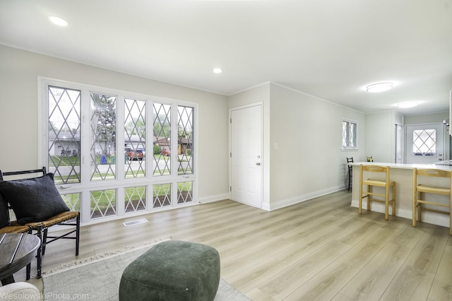 living area featuring light wood-style floors, baseboards, recessed lighting, and ornamental molding