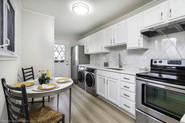 kitchen featuring stainless steel electric stove, a sink, independent washer and dryer, under cabinet range hood, and light countertops