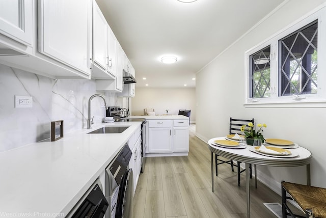 kitchen featuring light wood finished floors, dishwasher, light countertops, a sink, and white cabinets