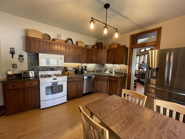 9600 W Shore Dr, Oak Lawn, IL 60453 - kitchen with appliances with stainless steel finishes, light wood finished floors, backsplash, dark countertops, and a sink