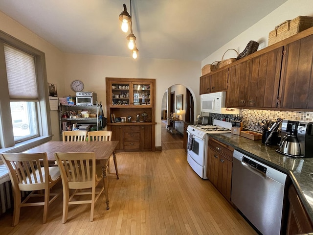9600 W Shore Dr, Oak Lawn, IL 60453 - kitchen featuring white appliances, arched walkways, decorative backsplash, light wood-style flooring, and dark countertops