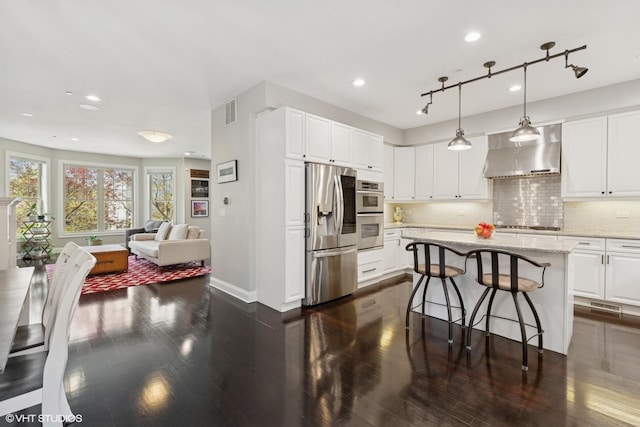 3447 N Whipple St, Chicago, IL 60618 - kitchen featuring stainless steel appliances, range hood, a breakfast bar, open floor plan, and white cabinetry