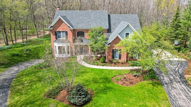 43W212 Tall Pines Rd, Campton Hills, IL 60124 - view of front facade featuring a chimney, roof with shingles, a front lawn, brick siding, and a wooded view