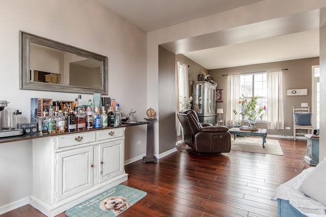 living room with a dry bar, dark wood-style flooring, and baseboards