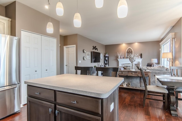 kitchen with freestanding refrigerator, dark brown cabinetry, light countertops, and dark wood-style flooring