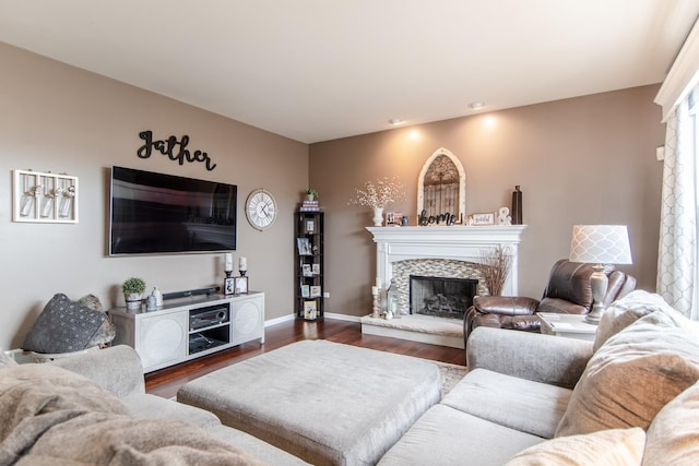 living room featuring dark wood-type flooring, a premium fireplace, recessed lighting, and baseboards