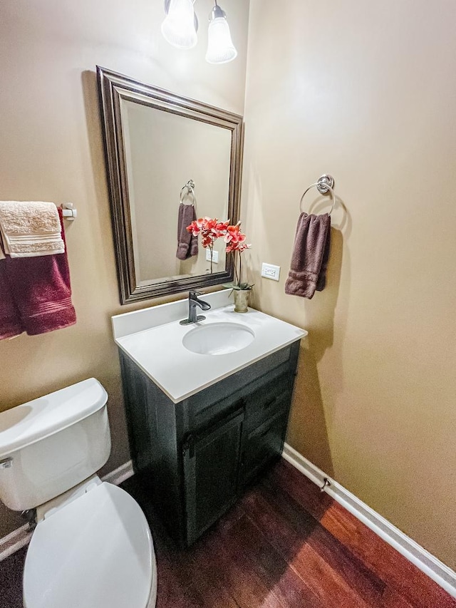 bathroom with wood finished floors, toilet, vanity, and baseboards