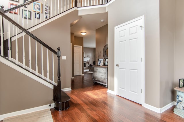 entryway with wood finished floors, baseboards, stairs, and a high ceiling
