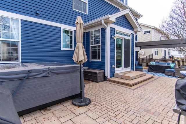 view of patio with an outdoor living space, fence, and a hot tub