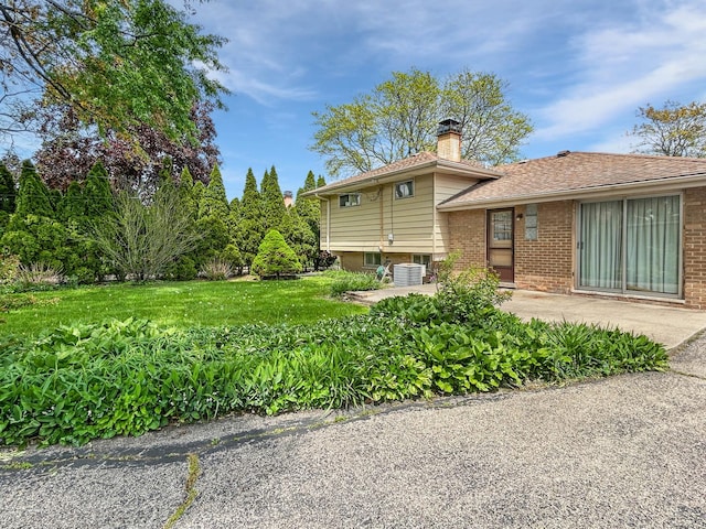 1048 Marshall Dr, Des Plaines, IL 60016 - view of home's exterior featuring a chimney, a patio area, brick siding, a yard, and central air condition unit