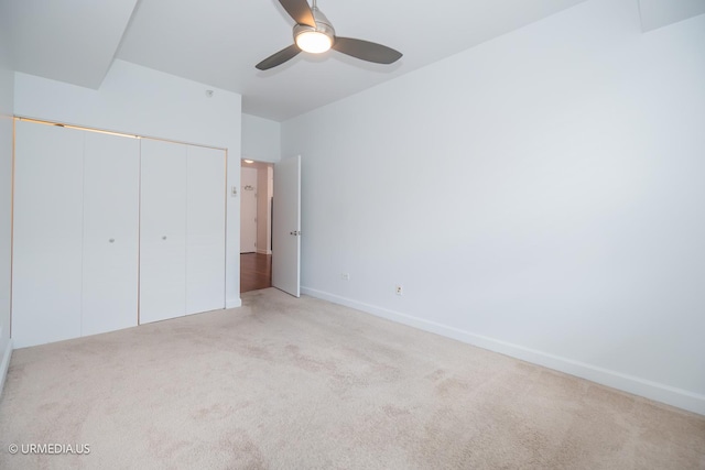 unfurnished bedroom with light colored carpet, a closet, baseboards, and ceiling fan