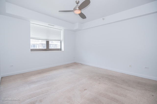 empty room featuring light colored carpet, ceiling fan, and baseboards