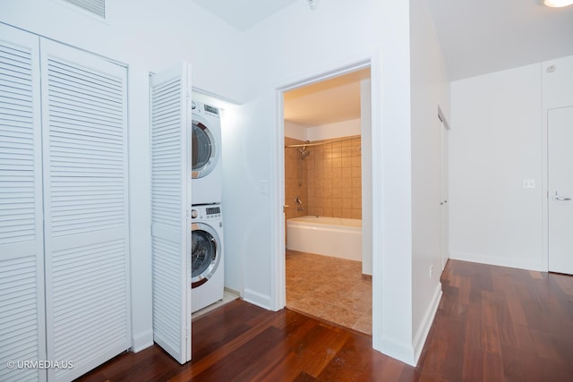 laundry room with stacked washer / drying machine and dark wood-style floors