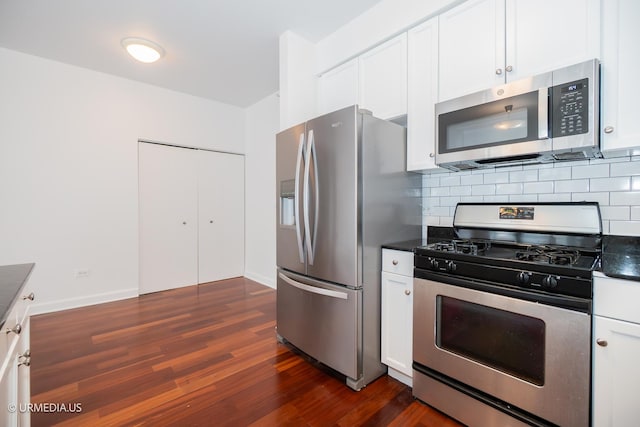 kitchen featuring appliances with stainless steel finishes, dark countertops, dark wood-style flooring, and white cabinets