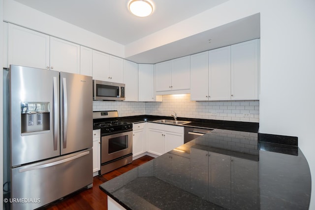 kitchen featuring stainless steel appliances, a sink, dark wood-style flooring, backsplash, and white cabinets