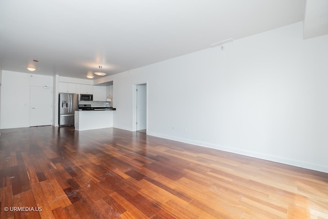 unfurnished living room with wood finished floors and baseboards