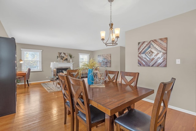 dining area with light wood-type flooring, healthy amount of natural light, and a chandelier